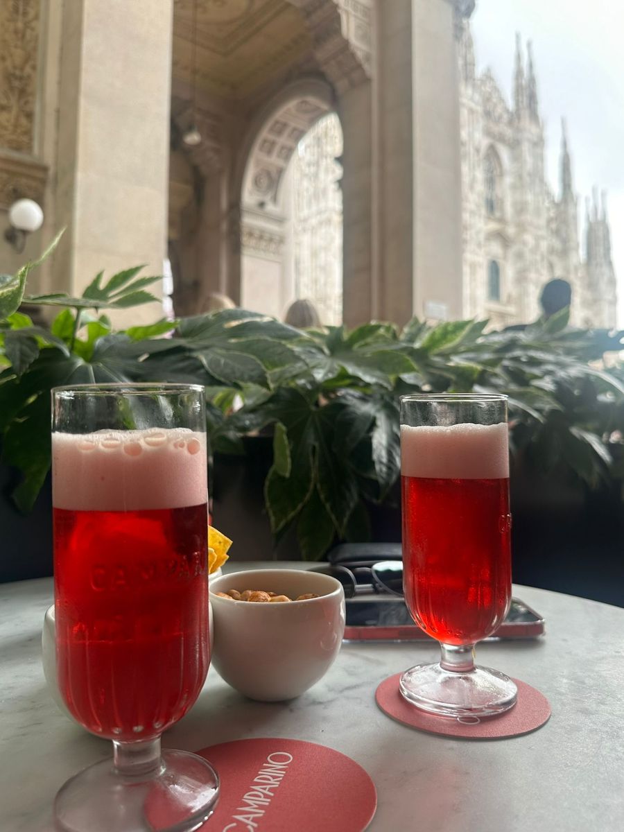Two Campari aperitivi on a marble table looking out at the Duomo in Milan