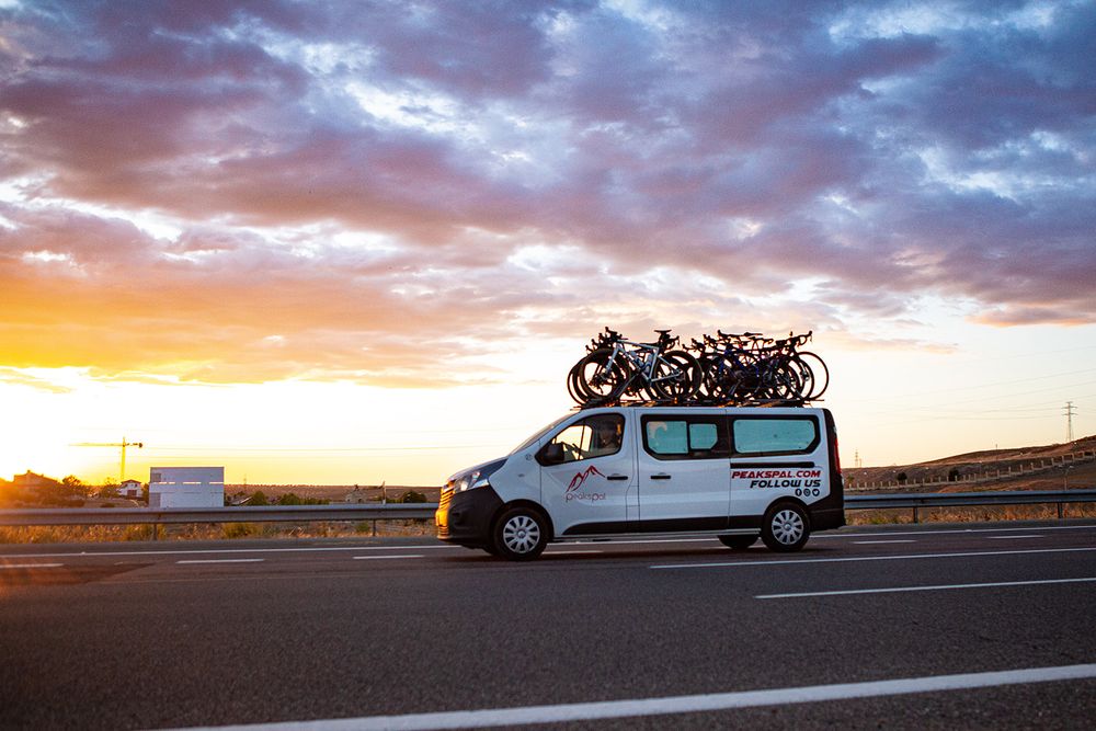 The PeaksPal support van on the road at sunset with bikes on the roof