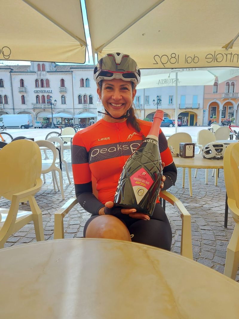 A PeaksPal rider in the piazza holding a bottle of Giro d Italia prosecco