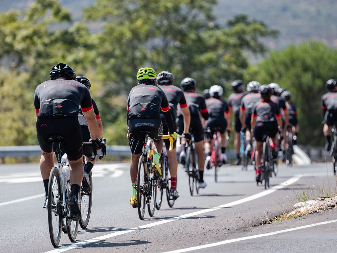 A long line of PeaksPal riders on an open road through the hills